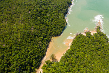Aerial drone view of a deserted tropical sandy beach surrounded by dense rainforest