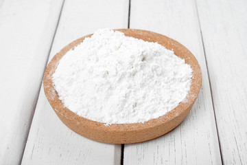 Flour on wooden plate over the white table