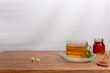 A glass cup of green natural tea and green tea leaf on the wooden table with tea plantations background, Healthy drink with copy space