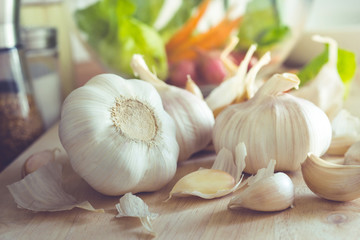 Group of garlic with blur vegetable on chopping board in kitchen room.Food and ingredient concepts
