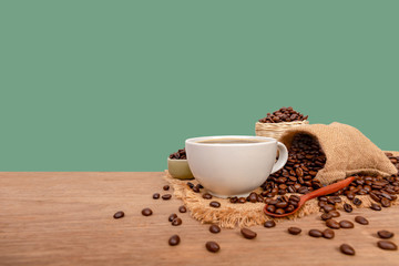 Hot cup of coffee  and beans with burlap sack on the wooden table, with copy space