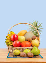 Composition with assorted fruits in wicker basket on wooden table, balanced diet, copy space