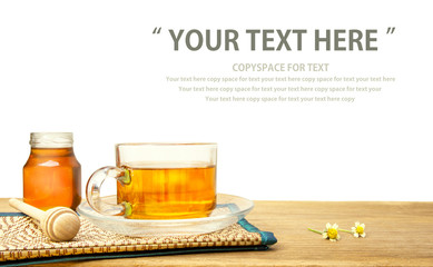 Hot tea cup and honey on the wooden table with tea plantations background. Healthy drink with copy space