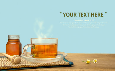 Hot tea cup and honey on the wooden table with tea plantations background. Healthy drink with copy space