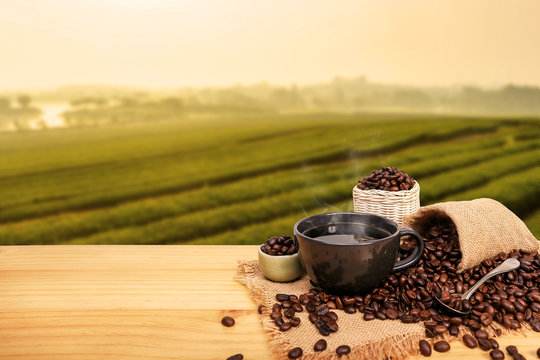 Hot cup of coffee and beans with burlap sack on the wooden table, with copy space