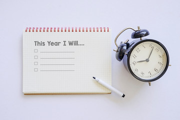 This Year I will word on notebook with black alarm clock, isolated white background. New Year...