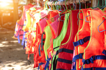 Life jacket orange color hanging on row. Life jackets, safety equipment prevent drowning. life security tool in water.
