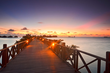 Obraz premium Long bridge heading to beautiful resort at Mabul Island during sunset.