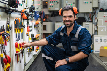 Caucasian marine engineer officer in engine control room ECR. He works in workshop and chooses...