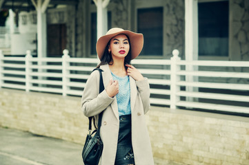Obraz premium Portrait of a young woman on the streets of the autumn city . A girl in a wide-brimmed felt hat and a light coat