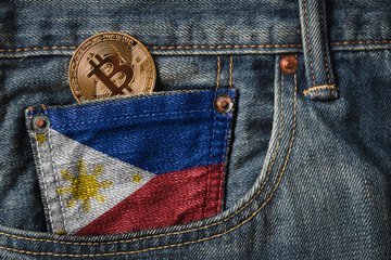 Golden BITCOIN (BTC) cryptocurrency in the pocket of jeans with the flag of Republic of the Philippines on Jeans Denim Texture. © ezstudiophoto