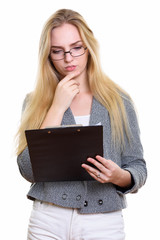 Studio shot of young beautiful businesswoman reading on clipboar