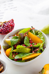 Persimmon salad with pear, pomegranate and pecan. Healthy vegetarian food concept.