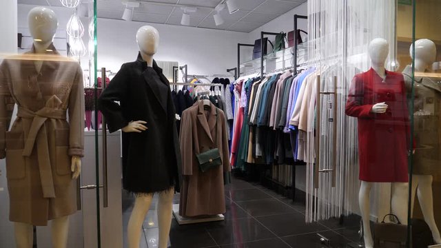 Coats and dress boutique store interior in a shopping mall center with hangers and mannequins