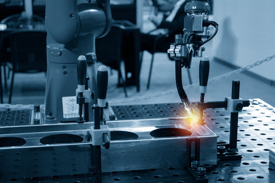 The welding robot machine for welding automotive part in the light blue scene.Industrial 4.0 concept for modern manufacturing process.