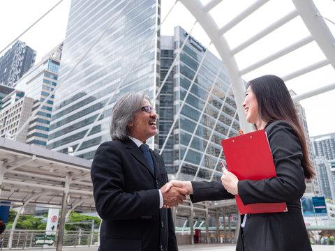 the old asian Businessman And young asian Businesswoman Shaking Hands with smile in the city . to show success or coperate in business.