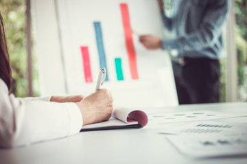 Hand of woman working with document front businessman giving a presentation to his employees in the meeting room.