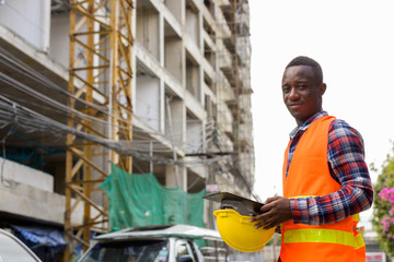 Young black African man construction worker holding clipboard an