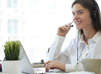 Female customer support operator with headset and smiling.