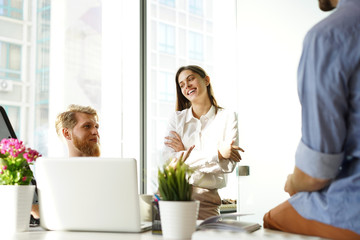 Young colleagues in smart casual wear working while spending time in the office.