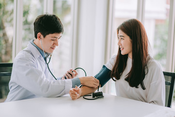 Doctor using sphygmomanometer with stethoscope checking blood pressure to a patient in the hospital.