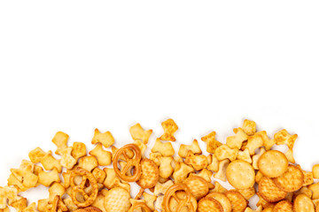 An assortment of salt crackers, sticks, pretzels, and fishes, shot from the top on a white background with a place for text. Party snacks mix with copy space