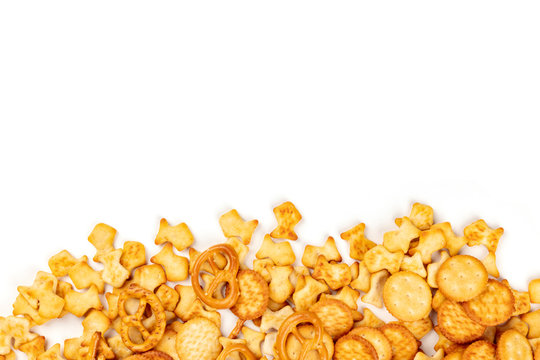 An assortment of salt crackers, sticks, pretzels, and fishes, shot from the top on a white background with a place for text. Party snacks mix with copy space