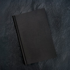 A black book, shot from above on a black background with copy space