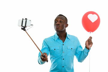 Studio shot of young black African man holding red balloon with 