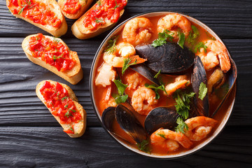 Bouillabaisse soup with seafood and fish close-up in a bowl served with toasts. horizontal top view