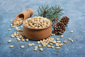 Fototapeta na wymiar Close-up on healthy and tasty pine nuts in wooden rustic bowl with wood scoop and cedar bump
