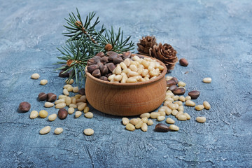 Fototapeta na wymiar Close-up on healthy and tasty pine nuts in small wooden rustic bowl with cedar bump and branch