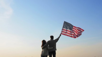 Married couple with large flag of America outdoors - Powered by Adobe