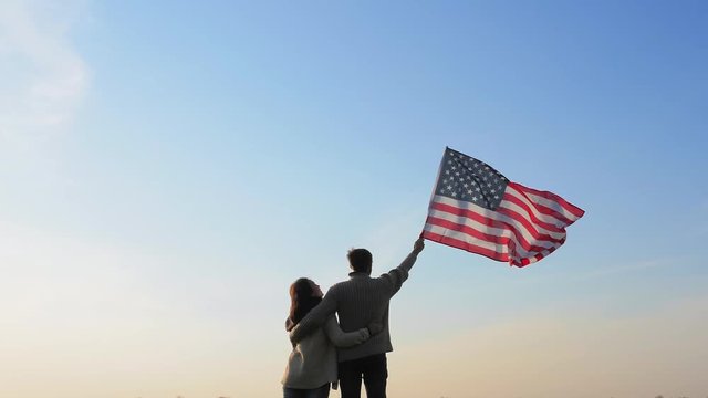 Married couple with large flag of America outdoors