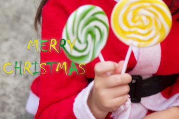 little girl dressed as santa claus with lollipops in her hand
