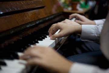 Obraz premium Children play piano in four hands