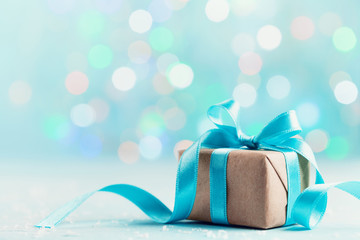 Christmas gift box against blue bokeh background. Holiday greeting card.