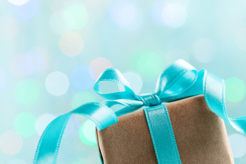 Christmas gift box against turquoise bokeh background. Holiday greeting card.