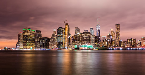 Fototapeta na wymiar Manhattan panoramic skyline at night. New York City, USA. Office buildings and skyscrapers at Lower Manhattan (Downtown Manhattan)..