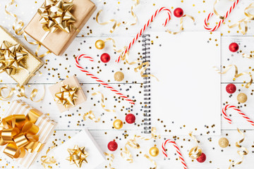 Christmas background of golden confetti, gift or present boxes, notebook and holiday decorations top view. Flat lay.