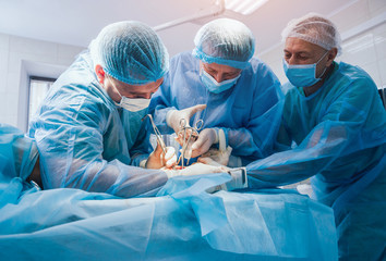 Process of trauma surgery operation. Group of surgeons in operating room with surgery equipment.