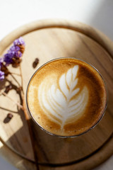 cup of coffee with art milk foam on wooden background