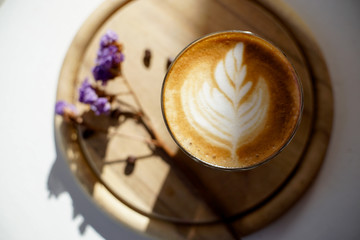 cup of coffee with art milk foam on wooden background