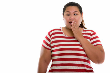 Studio shot of young fat Asian woman looking shocked while cover