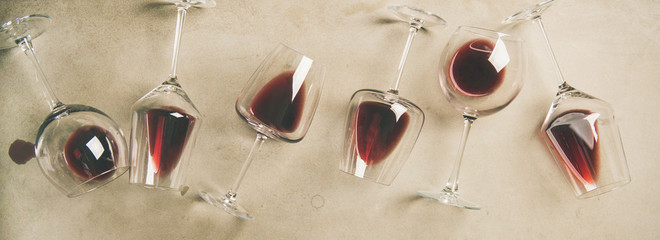 Flat-lay of red wine in glasses over grey concrete background, top view, copy space, wide composition. Bojole nouveau, wine bar, winery, wine degustation concept