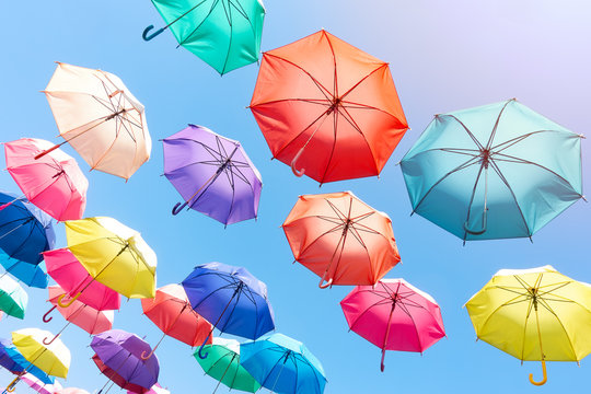 colorful umbrellas hang on to bright blue sky background