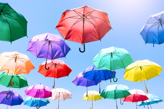 colorful umbrellas float on to bright blue sky background