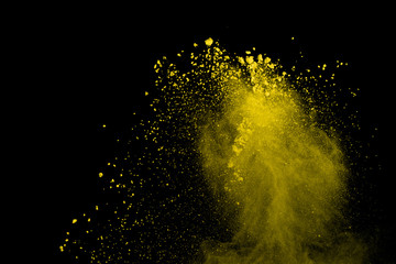 Abstract of yellow powder explosion on black background. Yellow powder splatted isolate. Colored...
