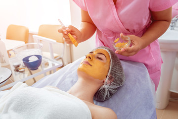 Obraz na płótnie Canvas Facial cosmetic procedure in spa salon. The procedure for applying a mask to the face of a beautiful woman