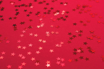 Beautiful festive red background with metallic star shaped confetti. Christmas decoration concept.
